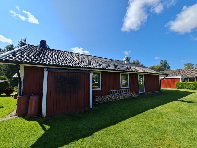 Nytvättat och nymålat tegeltak på röd villa i Sandhem – medarbetare arbetar på taket